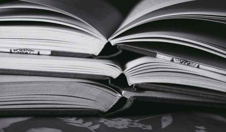 Artistic monochrome image of stacked open books, highlighting their pages and textures.