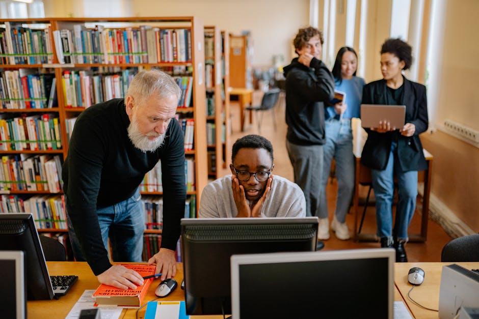 The Voice Behind the Screen Students and a mentor collaborate in a university library, engaging in educational activities.